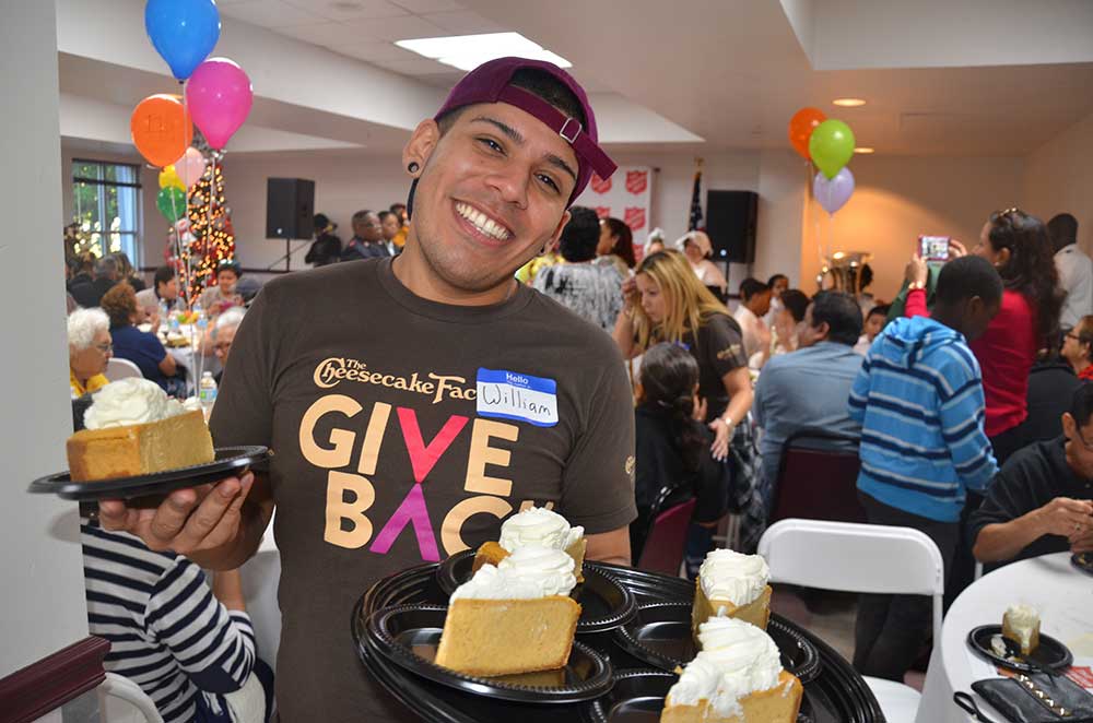 A Cheesecake Factory team member serves Pumpkin Cheesecake at The Salvation Army on Thanksgiving Day